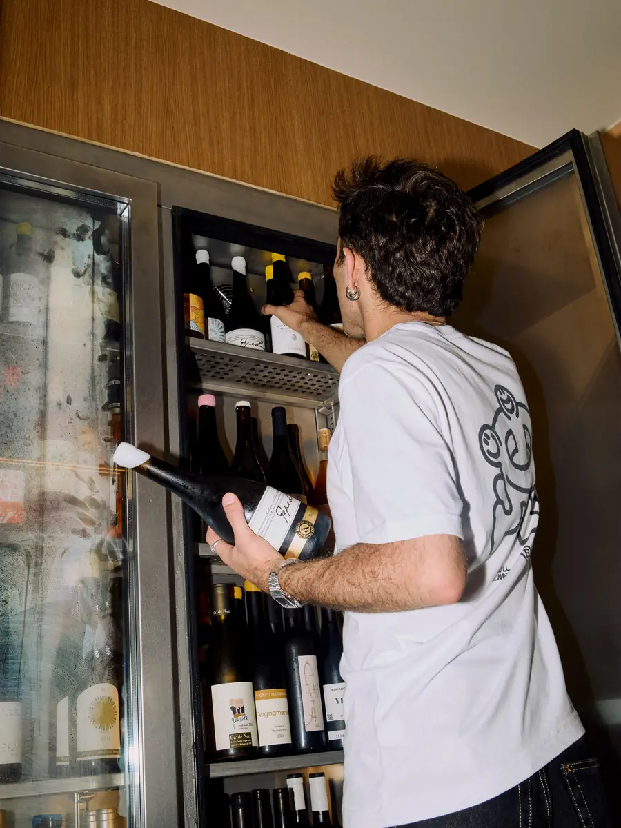 A waiter takes a bottle of wine out of the fridge