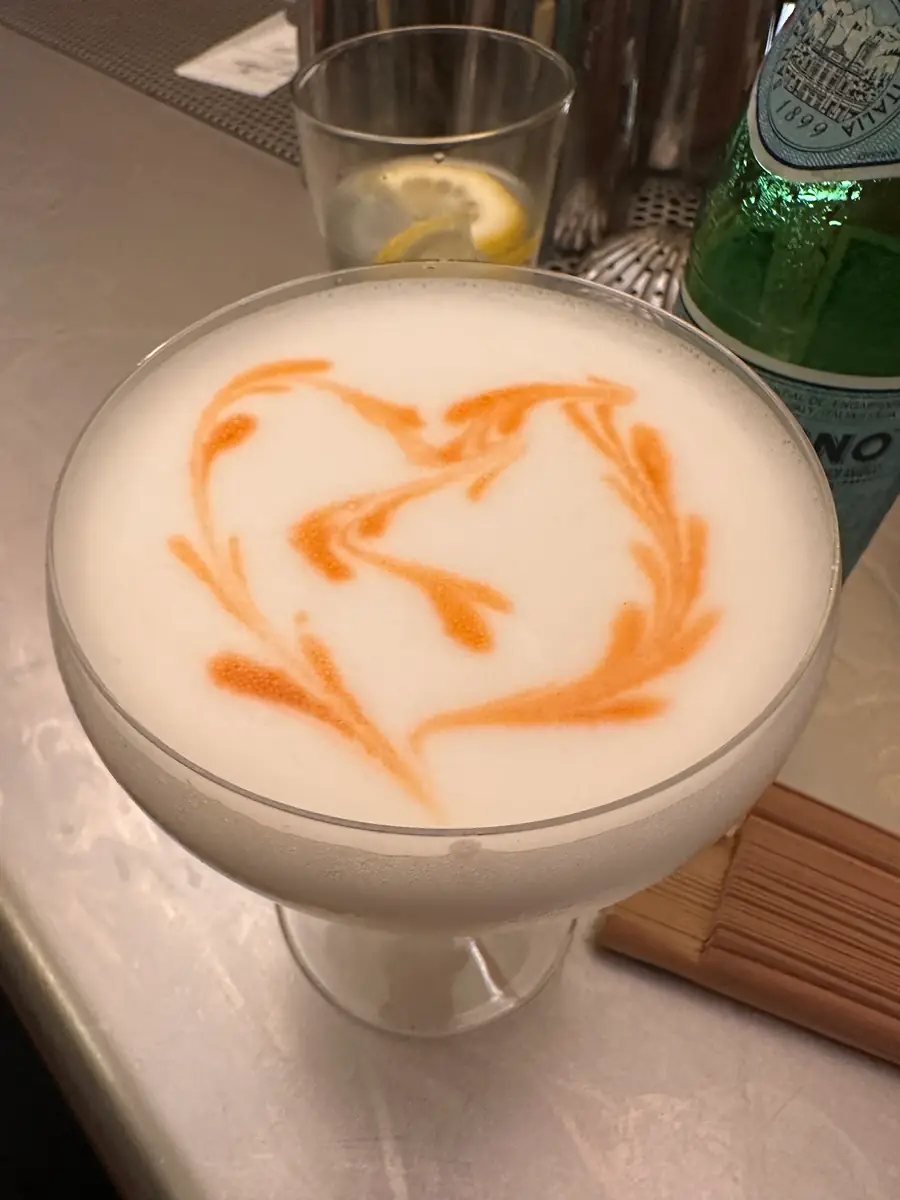 A house cocktail with foam and an orange drawing on top