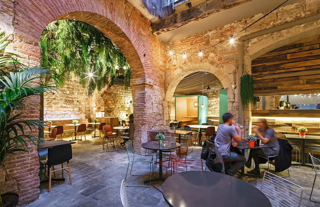 Los arcos de la terraza, con plantas colgando y mesas ocupadas