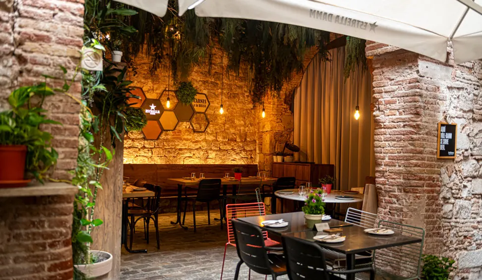 El comedor bajo un arco de piedra, con plantas y luz cálida