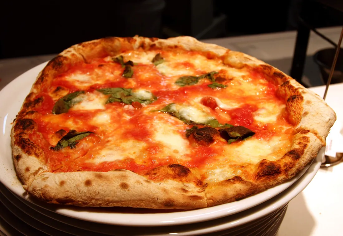 Pizza margherita con tomate, mozzarella y hojas de albahaca