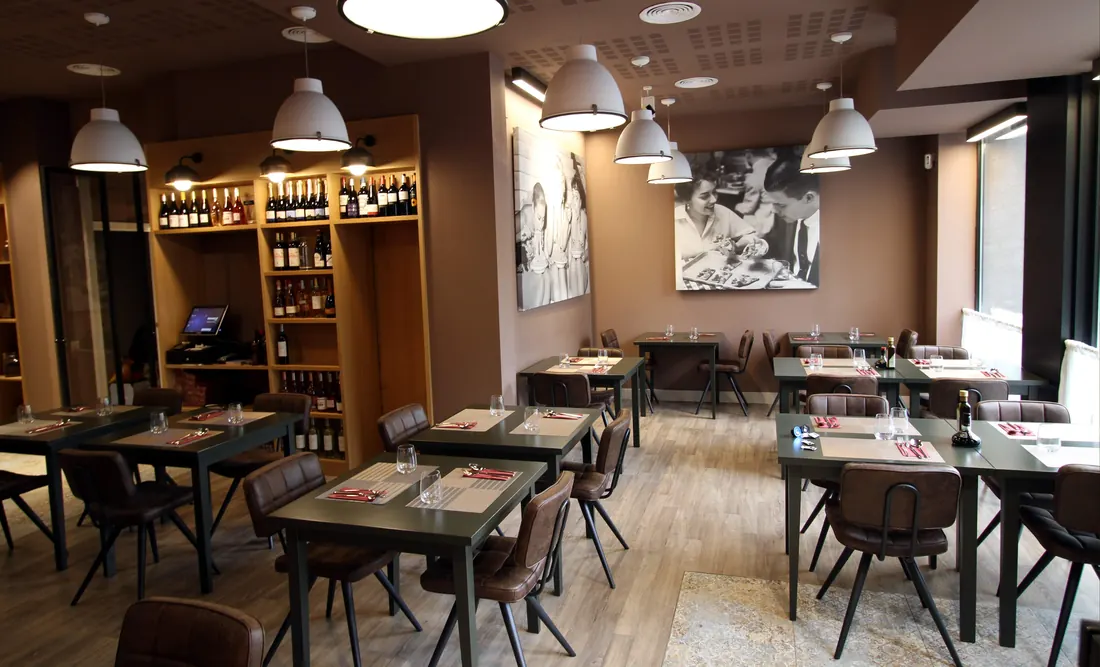 La sala de Via Napoli entera, con lámparas colgantes, murales en blanco y negro y la bodega al fondo