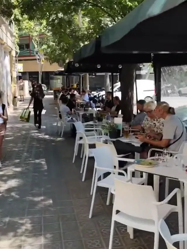 La terraza de Via Napoli bajo el toldo verde, con clientes en las mesas de la acera