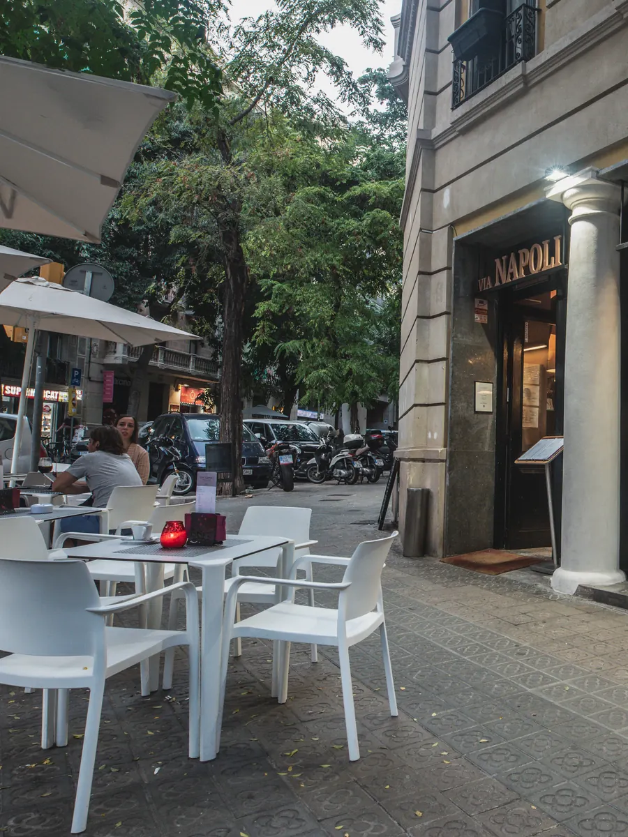 Mesas y sillas blancas de la terraza, junto a las columnas de la fachada